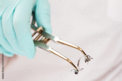 Dentist's hand in examination glove with dental tongs and clasp. photo