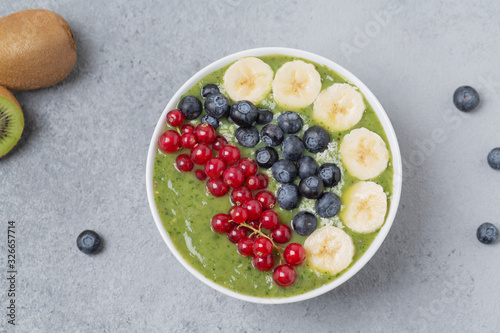 Breakfast detox green smoothie from kiwi, banana, spinach, red currant and blueberries in the bowl.