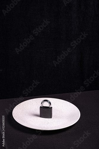The lock on the plate as a symbol of food restriction in the fight against obesity and gluttony
