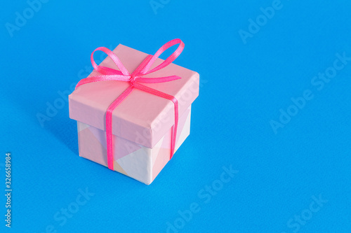 Gift box with ribbon and bow on a blue background. Selective focus. Space for text.