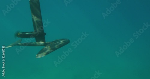 Under over view of a surfer hanging five on an electric hydrofoil watercraft, the future of water vehicles is here with hydrofoil transportation