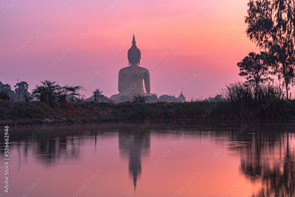 reflection of the biggest Buddha in the swamp at sunrise..the great Buddha of Thailand is the largest Buddha statue in the world at wat Muang Ang Thong Thailand.