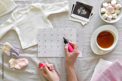 Top vew of expecting pregnant woman notes date of birth on the calendar, pregnancy and birth concept