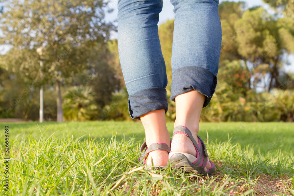 woman in sandals walking on green and long grass woman in sandals walking on green and long grass