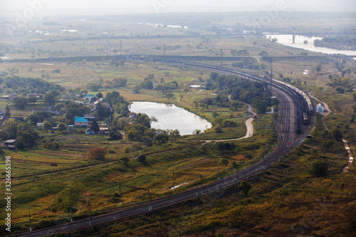 View from above. Beautiful panoramic view of the railway with freight trains passing near the wide river.