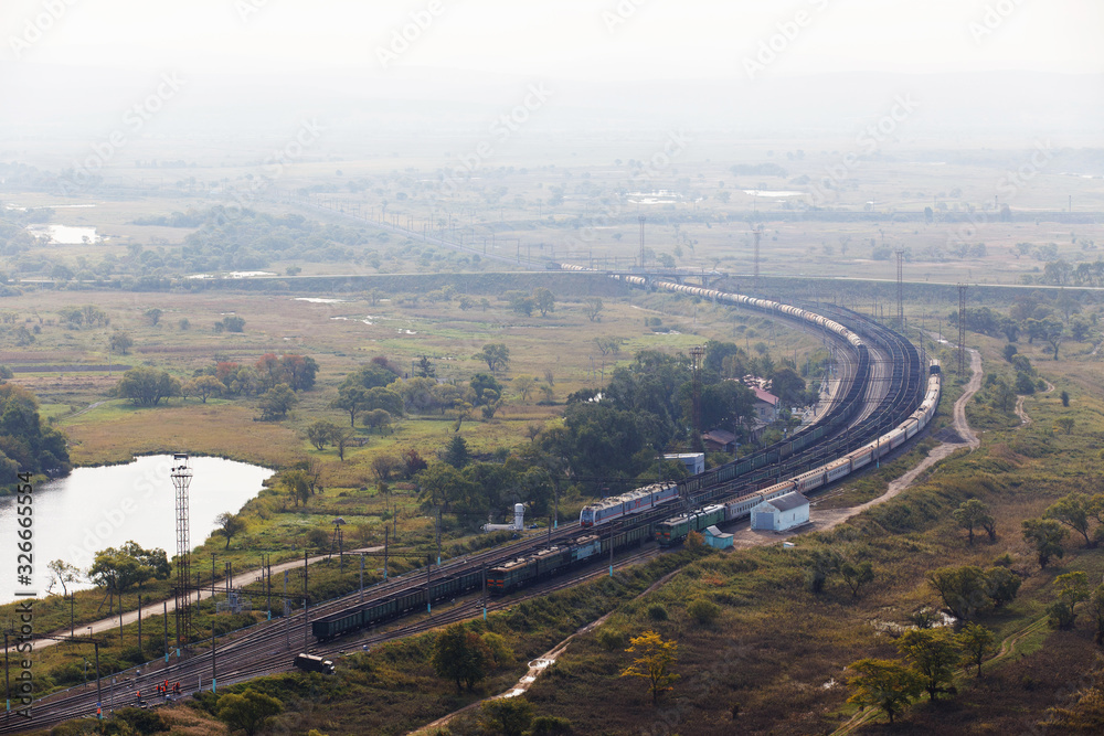 View from above. Beautiful panoramic view of the railway with freight trains passing near the wide river.