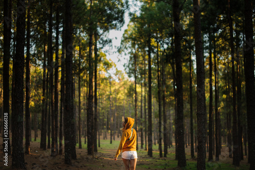 Female in stylish clothes stands in woods