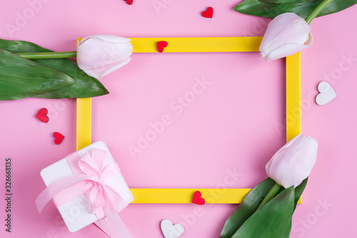 Fototapeta Naklejka Na Ścianę i Meble -  Festive invitation card with frame, fresh tulips flower and handmade paper gift box on a pastel pink background.