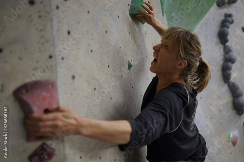 Female athletic climber, woman is climbing, bouldering at an indoor boulder rock hall