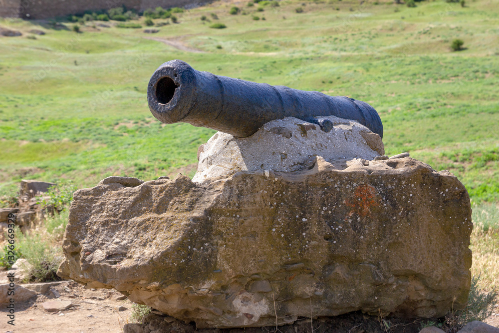 An ancient cannon in old Genoese fortress close up. Old cannon large. Antique black cannon. Genoese fortress, Sudak, Crimea. Historic old building. Monument of architecture.