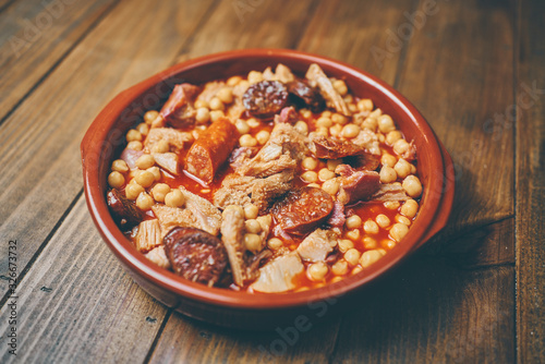 Garbanzos con callos en plato cerámico fondo madera photo