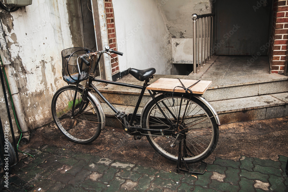 Vintage old bicycle with basket and wooden back seat on the alley.