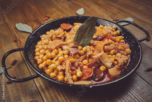 Garbanzos con callos en cazuela negra fondo madera photo