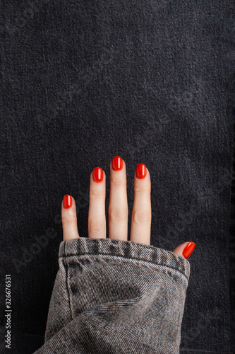 Open hand with red shiny manicure on a jeans background. Place for text