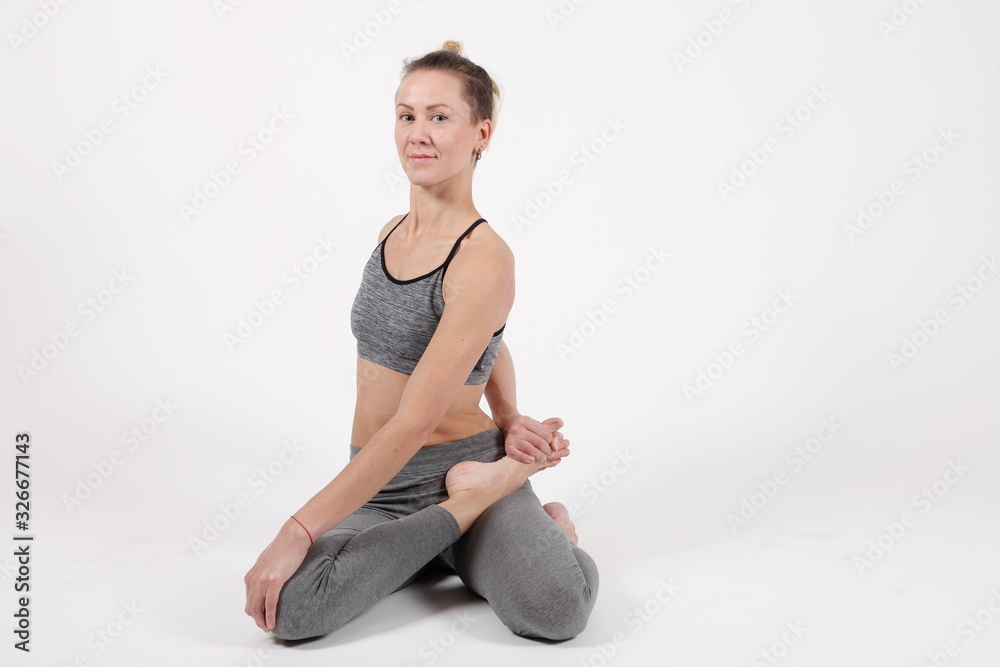 Young woman practicing yoga,standing in exercise leaning forward to straight legs, holding hands,toes,bharadvadjasana pose, balance workout,sportswear, pants,short,studio,white grey background Young woman practicing yoga,standing in exercise leaning forward to straight legs, holding hands,toes,bharadvadjasana pose, balance workout,sportswear, pants,short,studio,white grey background