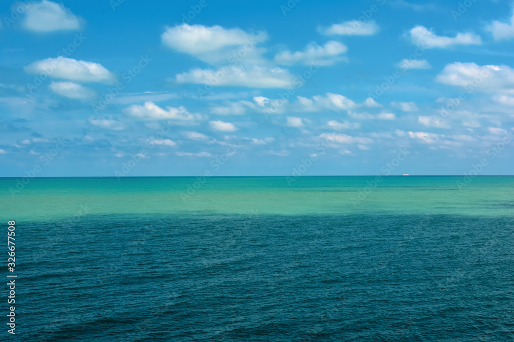 the sea surface is light turquoise and blue against a cloudy sky
