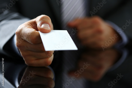 Male arm in suit give blank calling card to visitor closeup. White collar colleagues company name exchange, job interview, sale clerk id, executive or ceo, finance support, formal identity concept