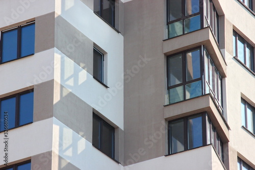 Parts of the modern facade of apartment buildings made of glass and concrete with highlights on the windows in beige colors. Trends in buildings