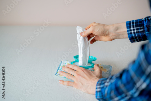 a caucasian male person taking a wet hygiene napkin and ckean his dirty hands