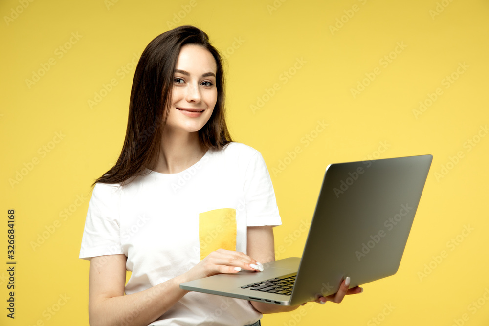 Naklejka premium woman with laptop on yellow background, copy space.