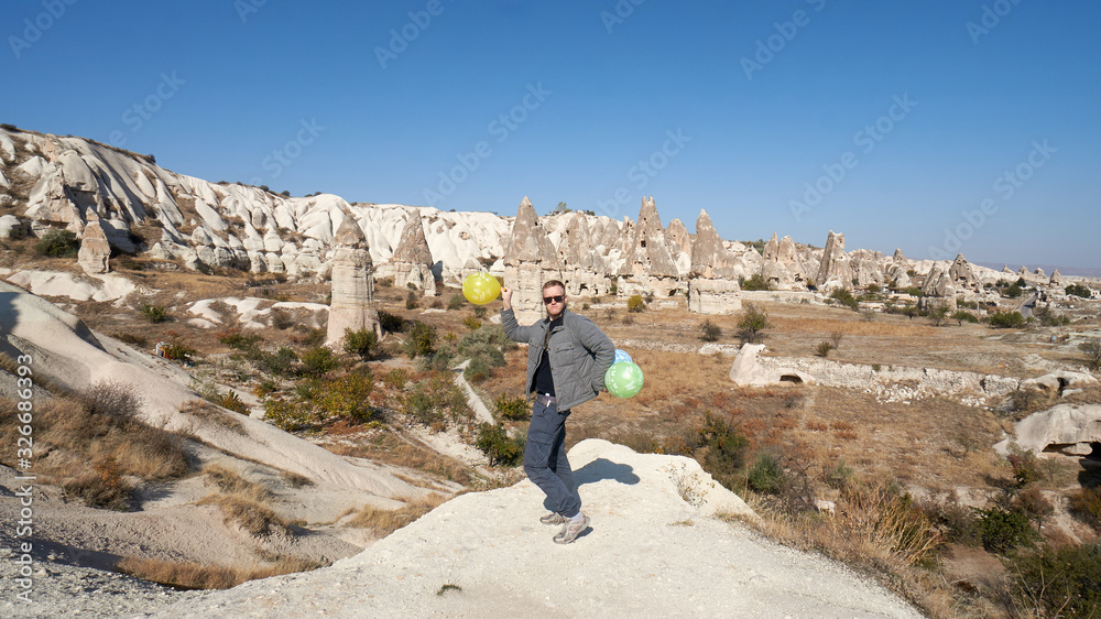 Young man with balloons celebrates his birthday in the Cappadocia desert, Turkey.
