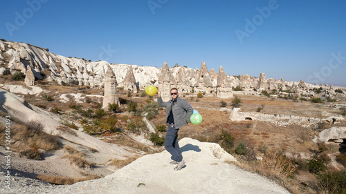 Young man with balloons celebrates his birthday in the Cappadocia desert, Turkey.