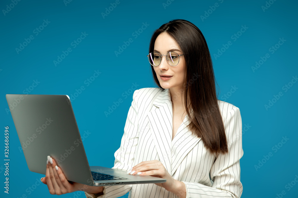 Smart beautiful young girl using laptop pc computer isolated on blue background Smart beautiful young girl using laptop pc computer isolated on blue background