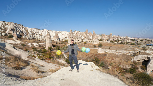 Young man with balloons celebrates his birthday in the Cappadocia desert, Turkey.