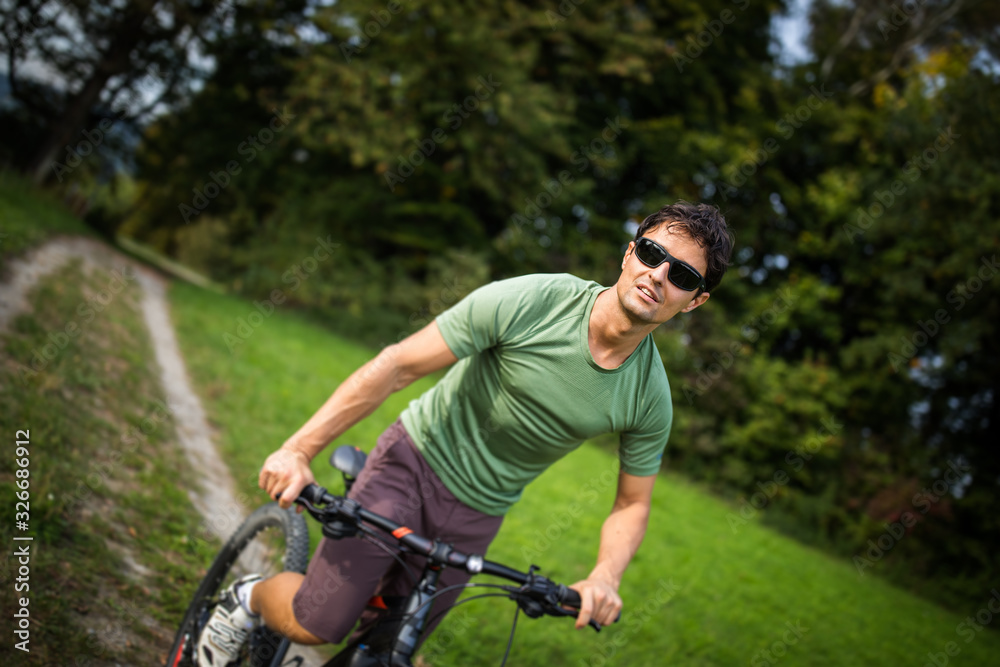 Fototapeta premium Young man riding his mountain bike outdoors on a forest path