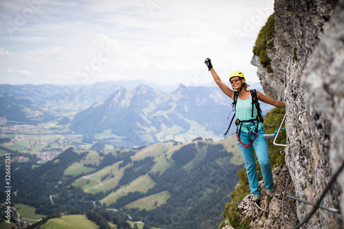 Pretty, female climber on a via ferrata -  climbing on a rock in Swiss Alps photo