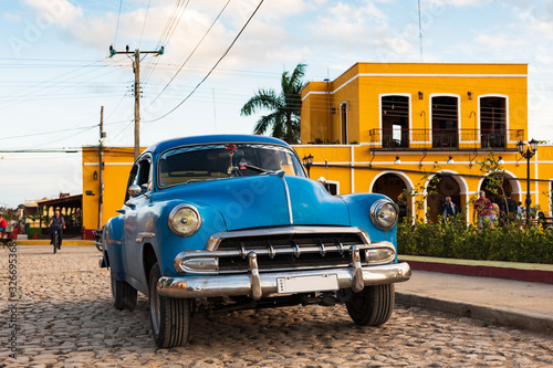 classic blue car on cobblestone road in front of colorful houses in trinidad, cuba © Michael Barkmann