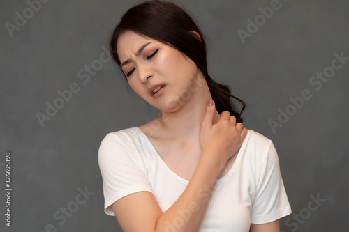 woman with shoulder or neck pain; portrait of asian woman suffering from shoulder or neck pain, stiffness, injury, chronic bone or muscle injury concept; asian young adult woman health care model