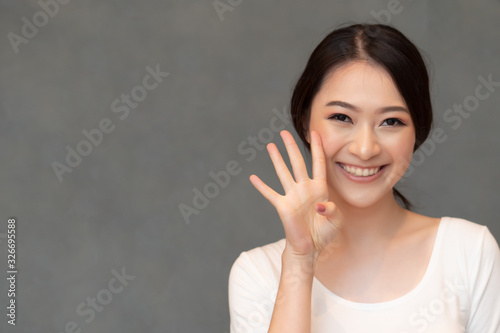 asian woman pointing, counting four finger; portrait of positive happy smiling asian woman pointing up 4 fingers for number four or 4 points concept ; Chinese asian adult woman model, casual theme photo