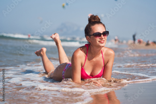 Young woman in pink bikini posing on a beach.