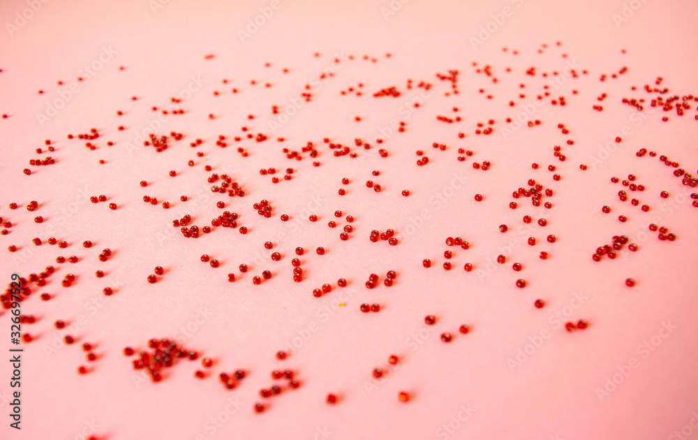 The handful of scattered red beads on a pastel light pink background. The handful of scattered red beads on a pastel light pink background.