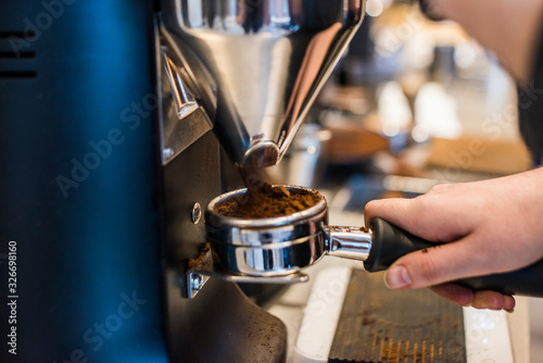 Espresso beans being ground to make espresso in coffee shop photo