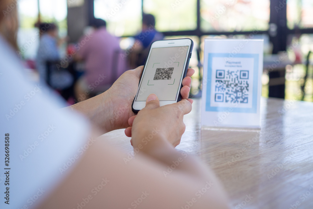 Women's hand uses a mobile phone application to scan QR codes in stores