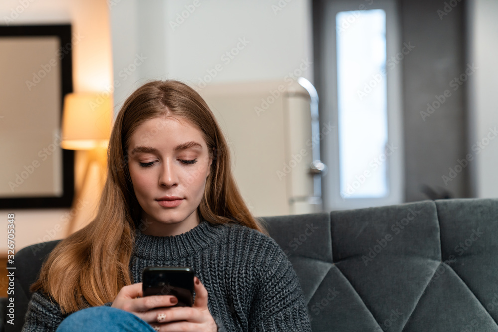 Woman indoors at home using mobile phone. Woman indoors at home using mobile phone.