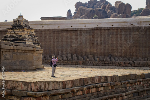 A tourist stands on the shore of a temple lake and shoots a photograph near Virupaksha Temple. Hampi, Karnataka photo