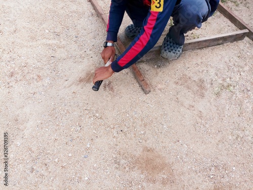 man walking on the beach. The carpenter is using the hammer to pull the nails out of the wood on the sandy background.