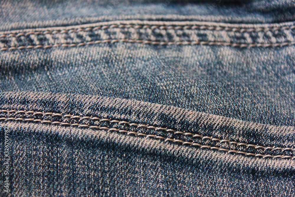 Blue jeans seams pattern. Casual denim blue jeans texture background, vintage jeans detail, stitch lines on denim fabric, clothing element close up top view Blue jeans seams pattern. Casual denim blue jeans texture background, vintage jeans detail, stitch lines on denim fabric, clothing element close up top view