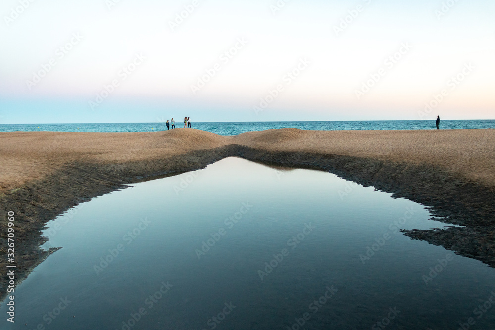  Puddle formed in the middle of the sand of Fenals beach located in Lloret de Mar