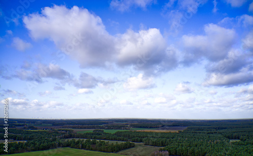 Cultural landscape of northern Germany with forests  fields and meadows under a blue and white sky with clouds