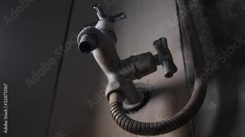 Water dripping from a dull old faucet, leaking water tap in a bathroom, slow motion