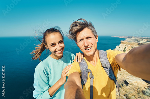 Cuadro en lienzo young man and woman tourist making selfie and smile to the camera on cliff edge with beautiful sea view and enjoying wonderful nature