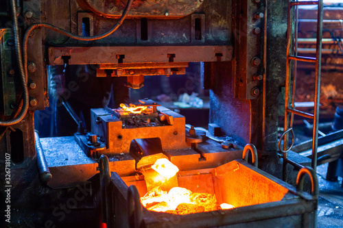 close-up picture of fresh forged hot steel workpieces after press forming in dirty dark factory photo