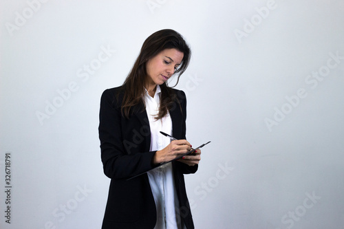 Portrait of attractive caucasian bussiness woman model with a folder in her hands, isolated on gray background studio shot, white shirt and black jacket, dark air. Place for your text in copy space.