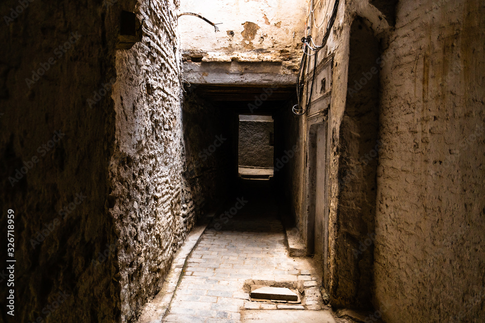 Claustrophobic tight stone streets in traditional medieval medina in Fes city, Morocco.