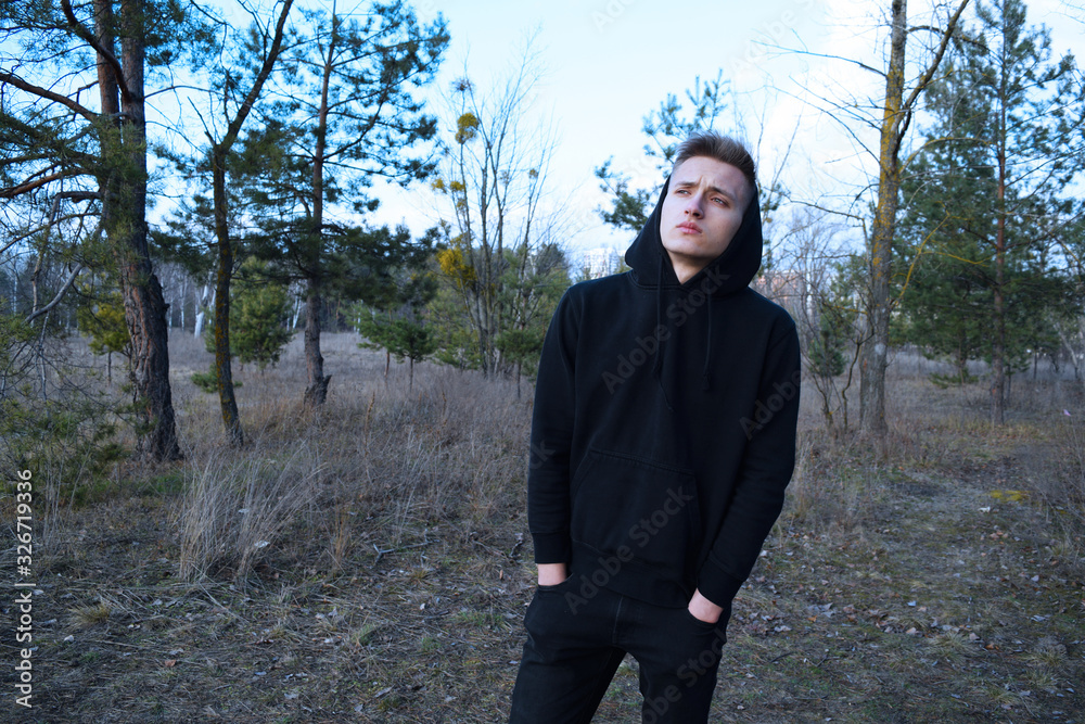 Young man in black clothes on the background of nature with dry plants.