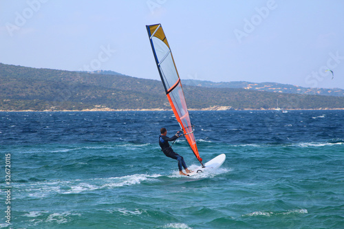 Windsurfing in the emerald green water of Sardinia (Porto Pollo, Italy)